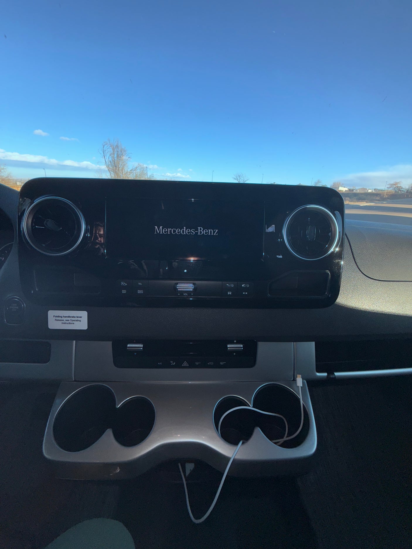 Modern Mercedes-Benz dashboard and infotainment display inside an RV rental, with air vents, climate controls, and cup holders.