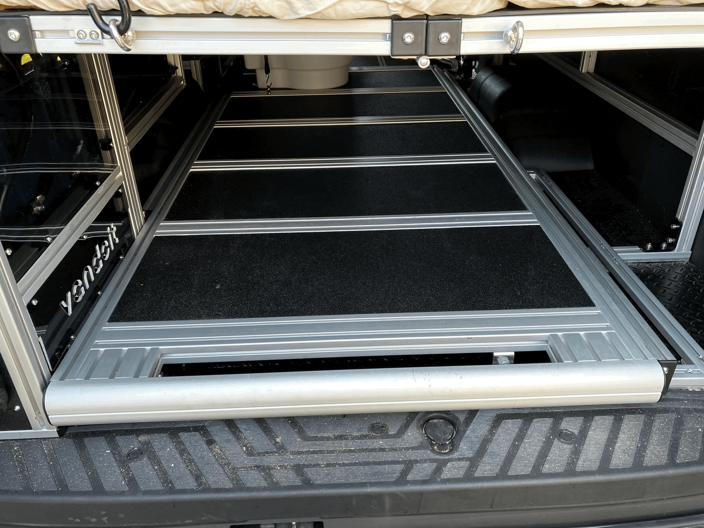This RV rental’s rear cargo area features a practical pull-out storage system under an elevated bed.