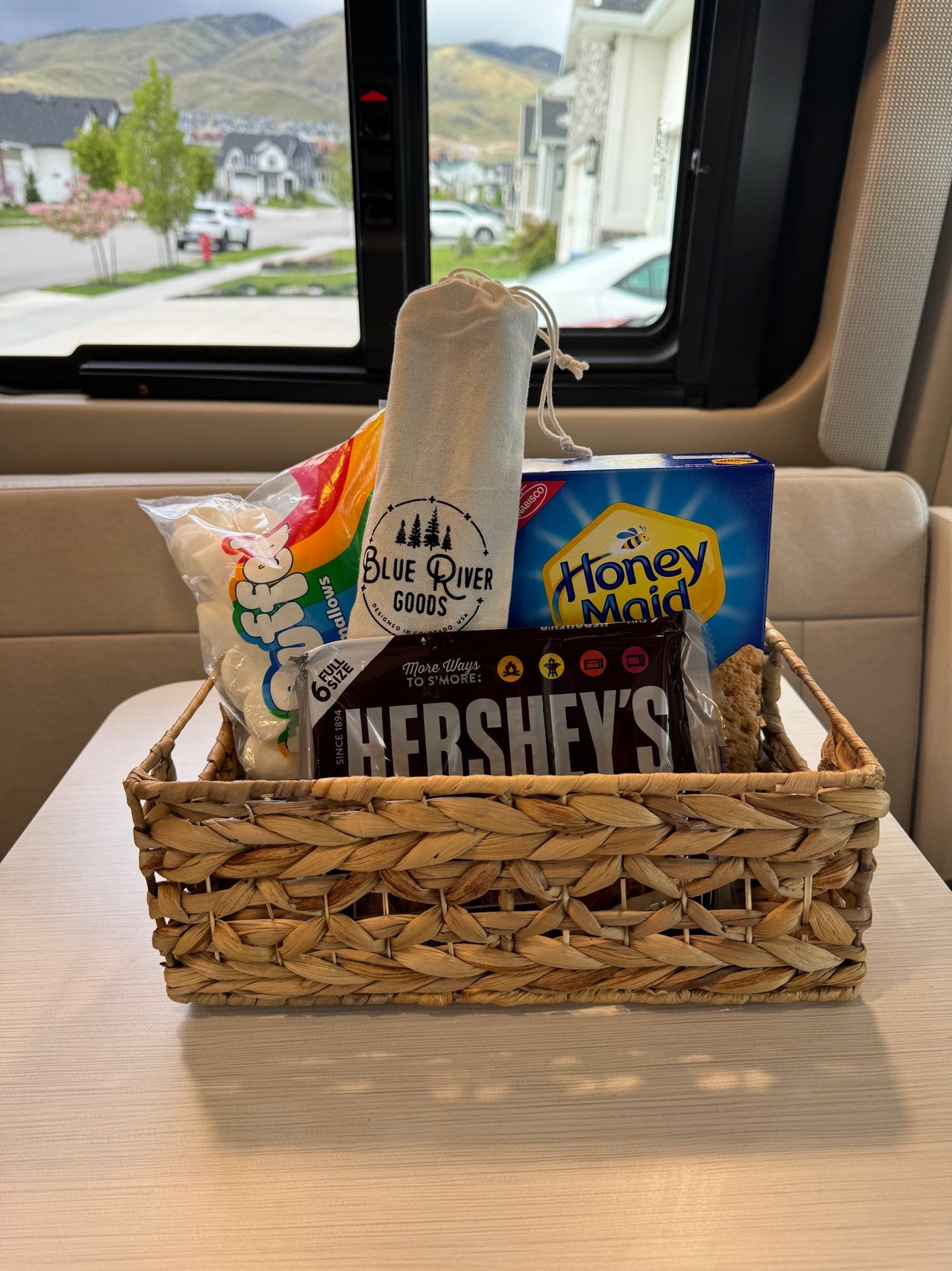 An RV rental welcome: s'mores kit (marshmallows, Hershey's, Honey Maid, Blue River Goods) in a basket, ready for fun.