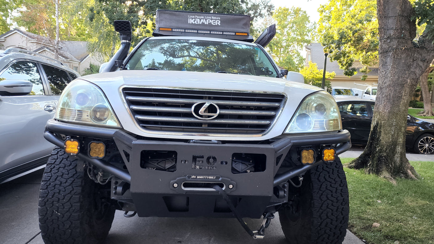 Front view of a white, modified Lexus GX with an iKamper rooftop tent & winch. An ideal off-road rv rental for adventure trips.