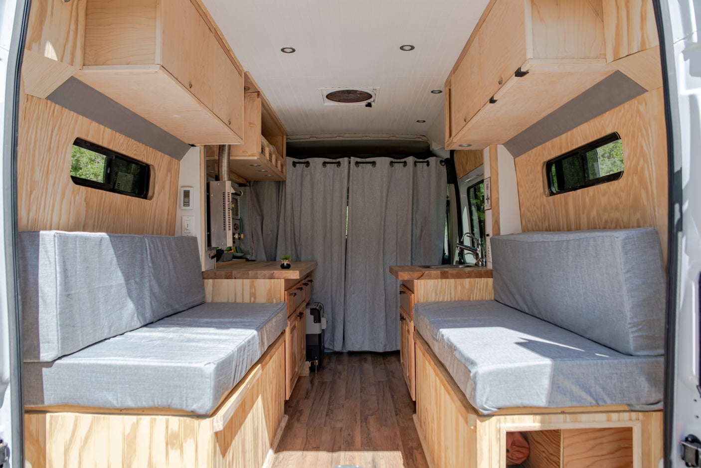 Spacious custom RV rental interior featuring wood paneling, comfortable benches, and a full kitchen setup.