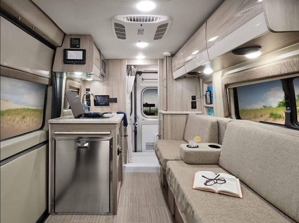 This RV rental offers a compact kitchen, comfy lounge with book/drink, and control panels. Ideal for mobile living.