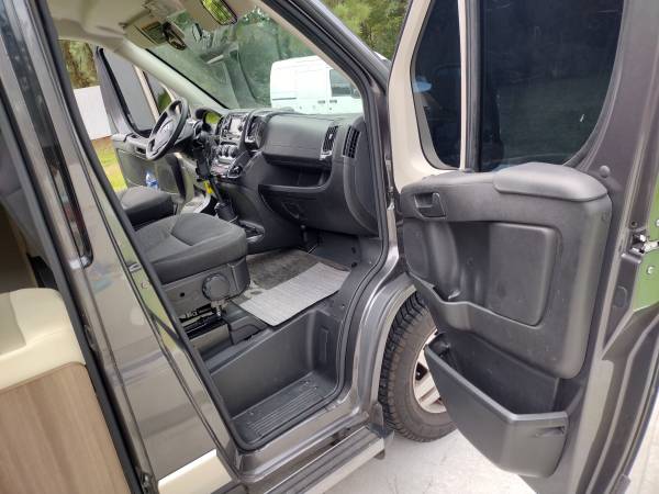 parked in a lot under a cloudy sky.|Dark grey Travato RV rental