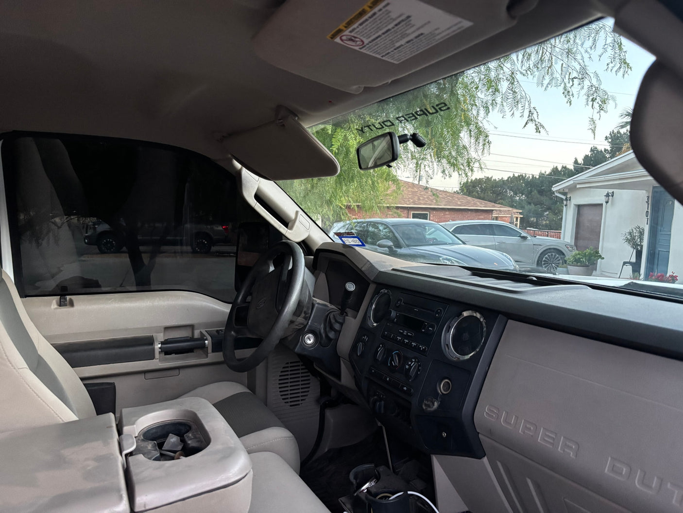 View from inside a Ford Super Duty truck's cab, showing dashboard & steering wheel. Residential street outside. For your RV rental adventure.