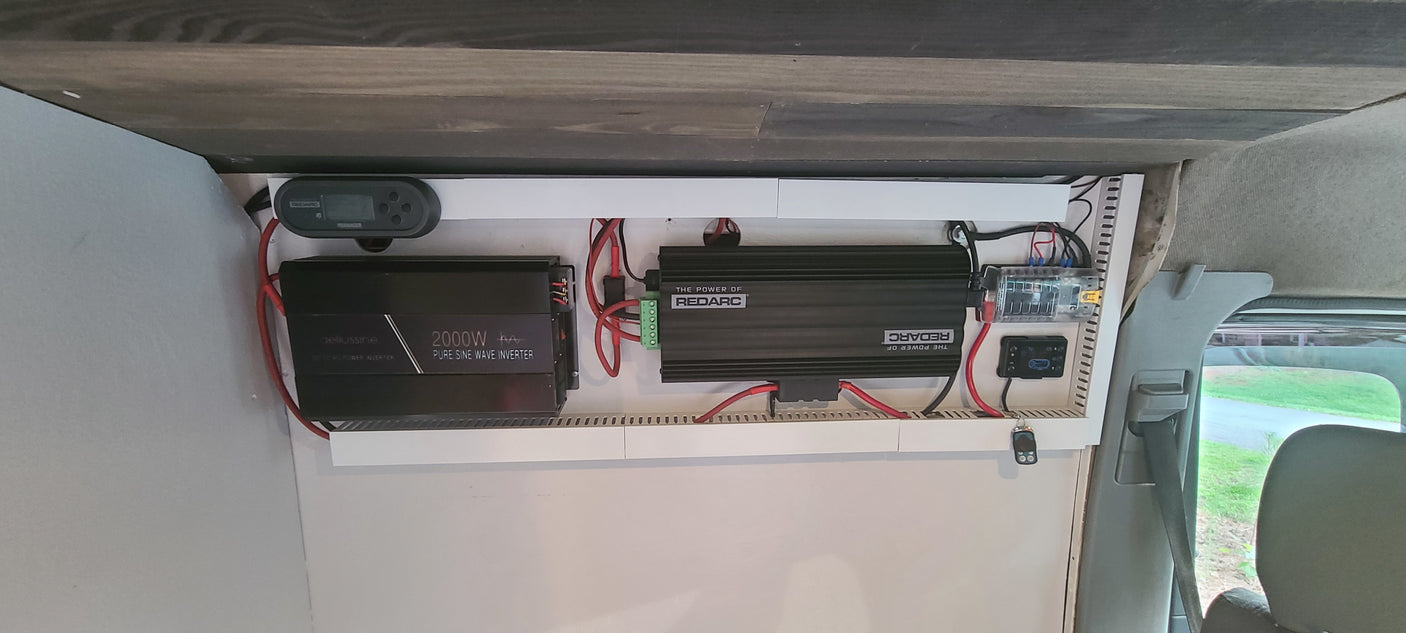 RV rental van's power system: Redarc manager, 2000W inverter, fuse box, and wiring for robust off-grid use.