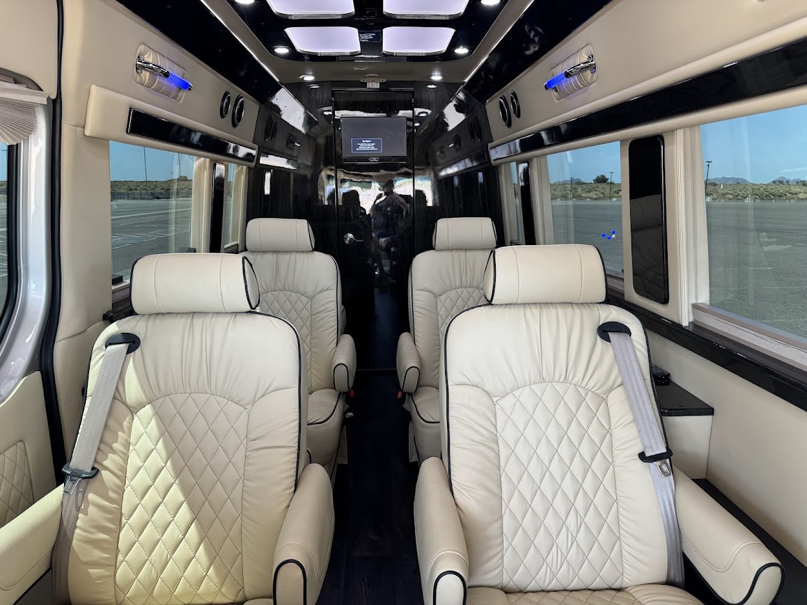 Spacious RV rental interior with luxurious cream-quilted leather captain's chairs, central aisle, and large windows. — photo 8