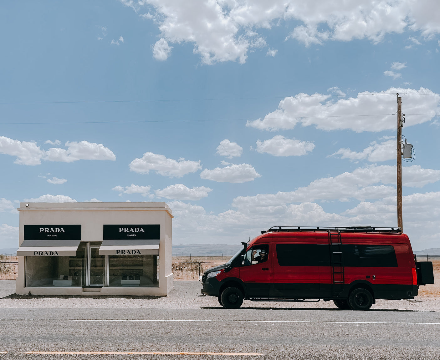 Red RV rental van at Prada Marfa desert art installation. Driver waves from the window.