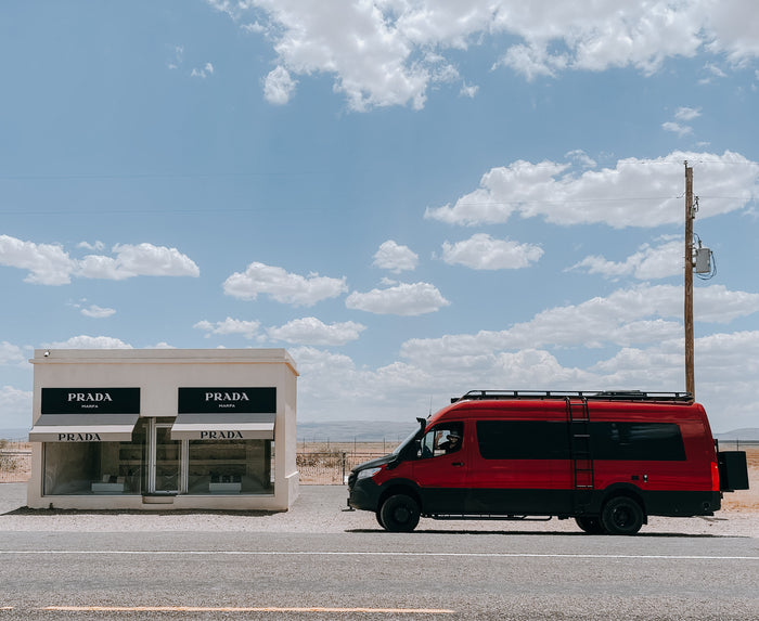 Red RV rental van at Prada Marfa desert art installation. Driver waves from the window.