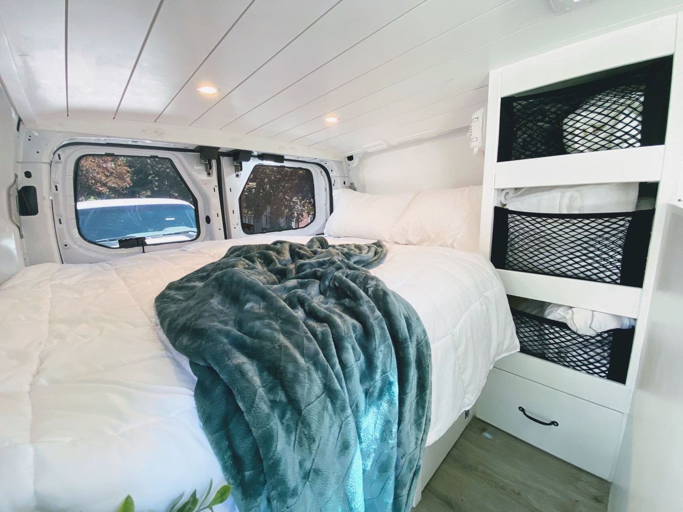 crucial for off-grid power.|RV rental: Portable Camco toilet next to a cozy bed with power outlets. Essential amenities for comfortable travel.|Explore this RV rental's light gray van interior featuring swiveling front seats and a safety fire extinguisher.|A hand with a key opens the shore power inlet on an RV rental
