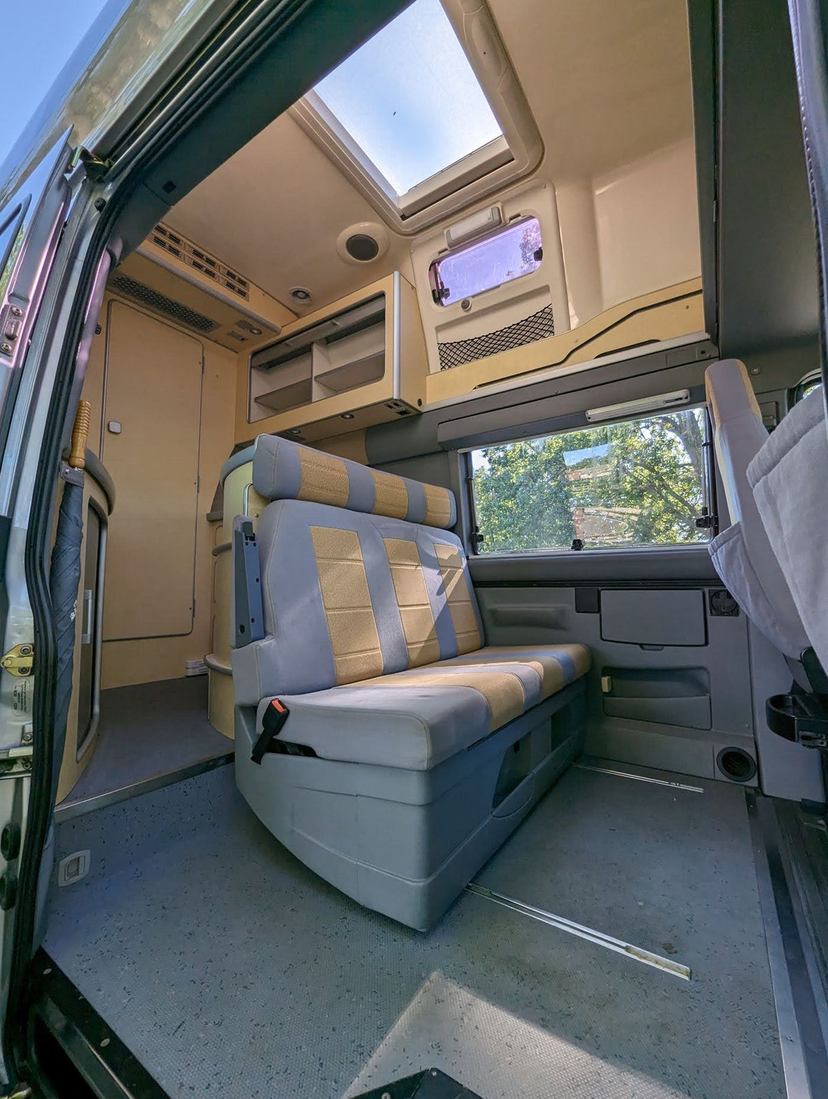 RV rental: Bright camper van interior with skylight, comfortable striped seating, and overhead storage. — photo 6