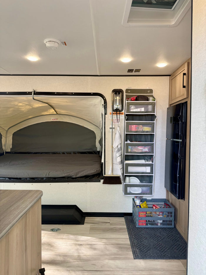 ready for outdoor adventure.|This Coleman travel trailer RV rental is parked on a dirt campsite among trees