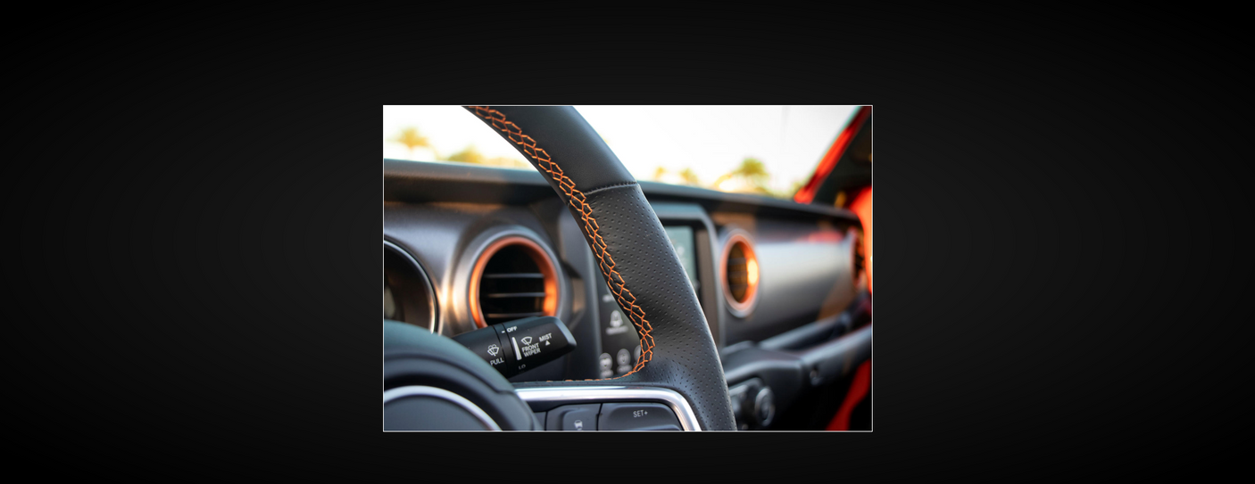 Adventure-ready RV rental interior: black steering wheel with orange stitching, and highlighted dashboard accents.