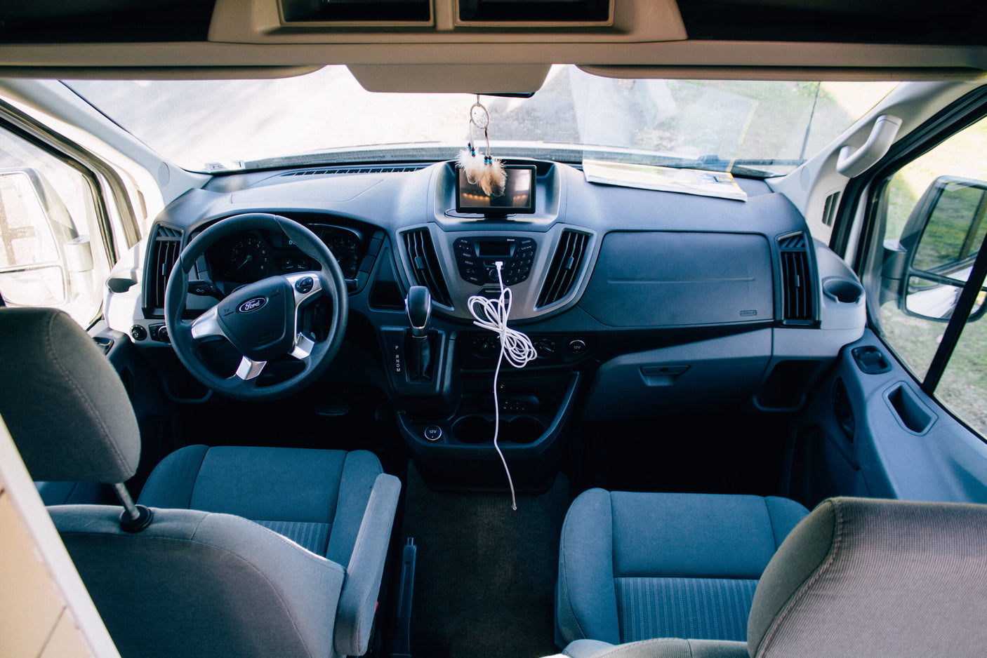 This image displays the clean and functional front cabin interior of a Ford Transit RV rental van, ready for your next adventure.