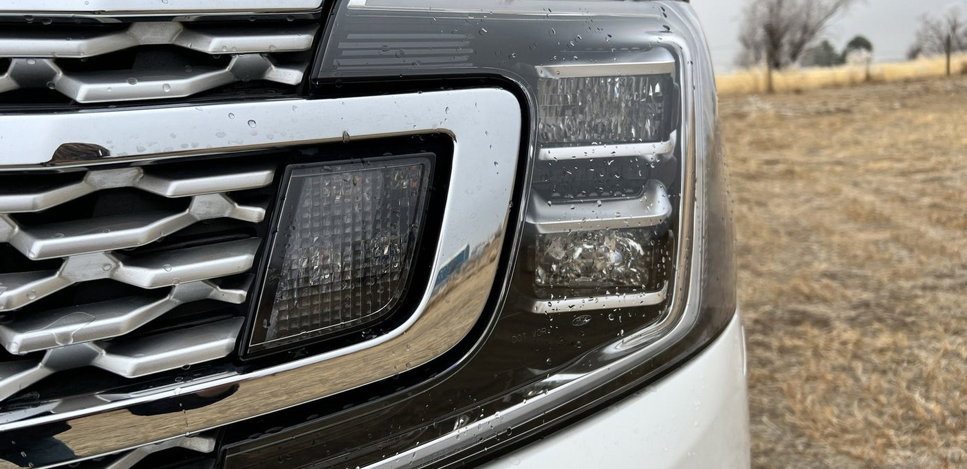 Rain-splashed grille and modern LED headlight of a large SUV. Perfect for your RV rental adventure.