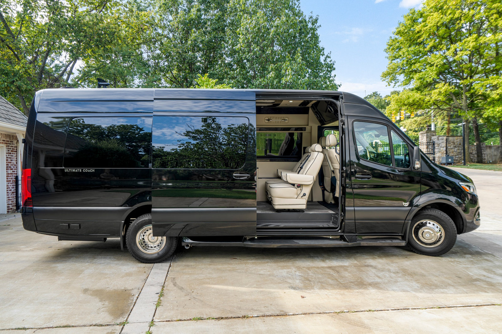 Black luxury RV rental van, side view. Open door reveals plush cream interior seating.