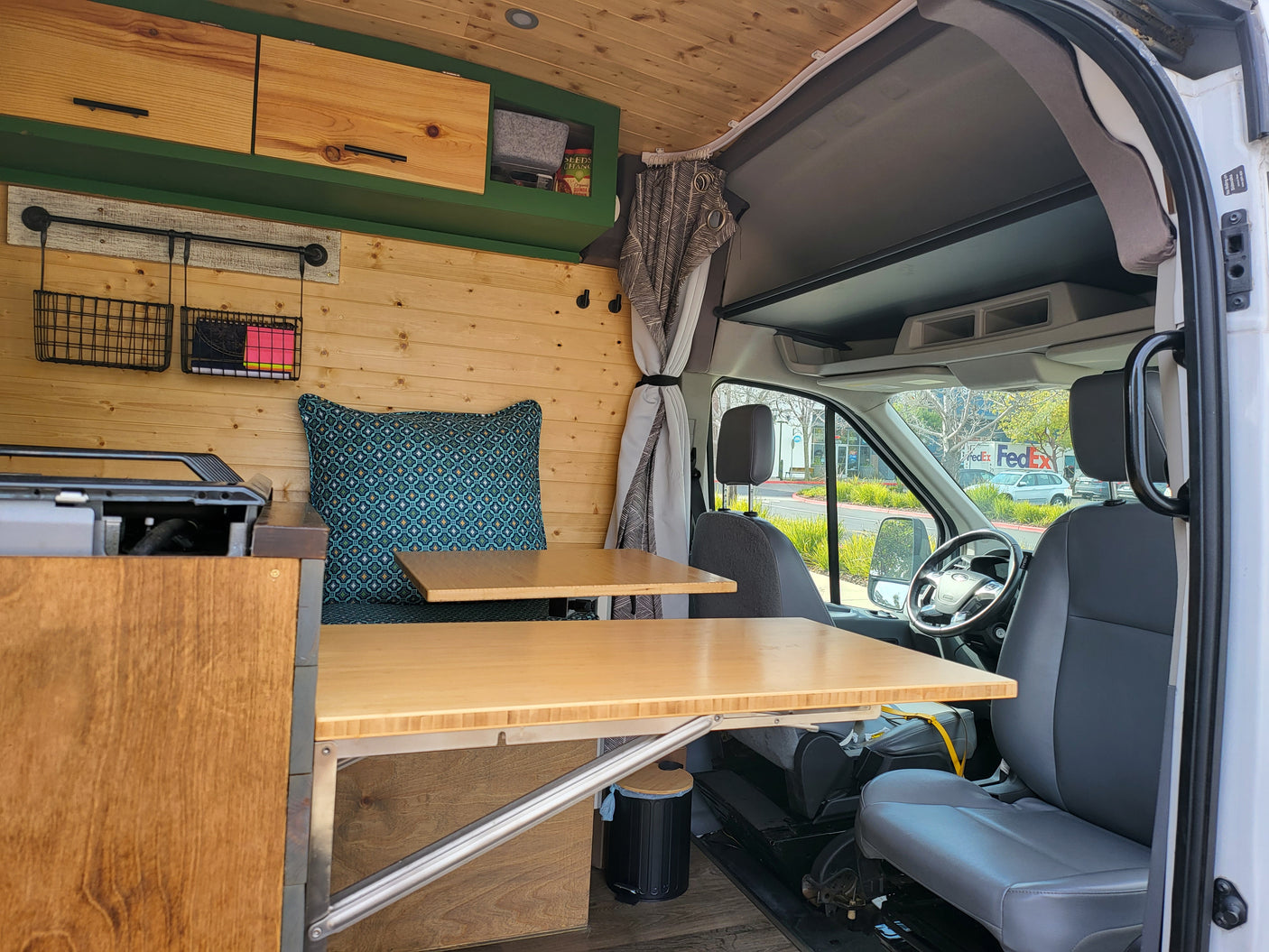 Inside a custom RV rental: wood-paneled camper van interior with adaptable tables, storage, and a comfy seating area.