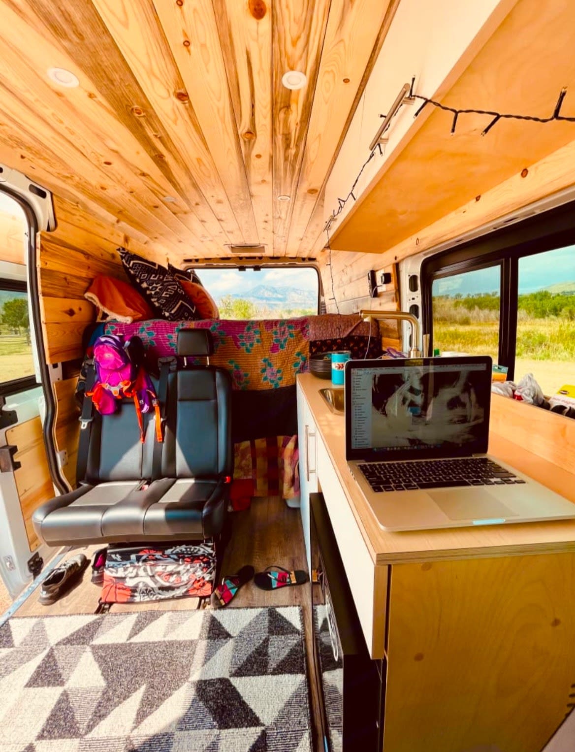 perfect for outdoor adventure.|Modern kitchen with coffee gear + a stunning desert view from the window.|Rear view of an RV rental: two beds