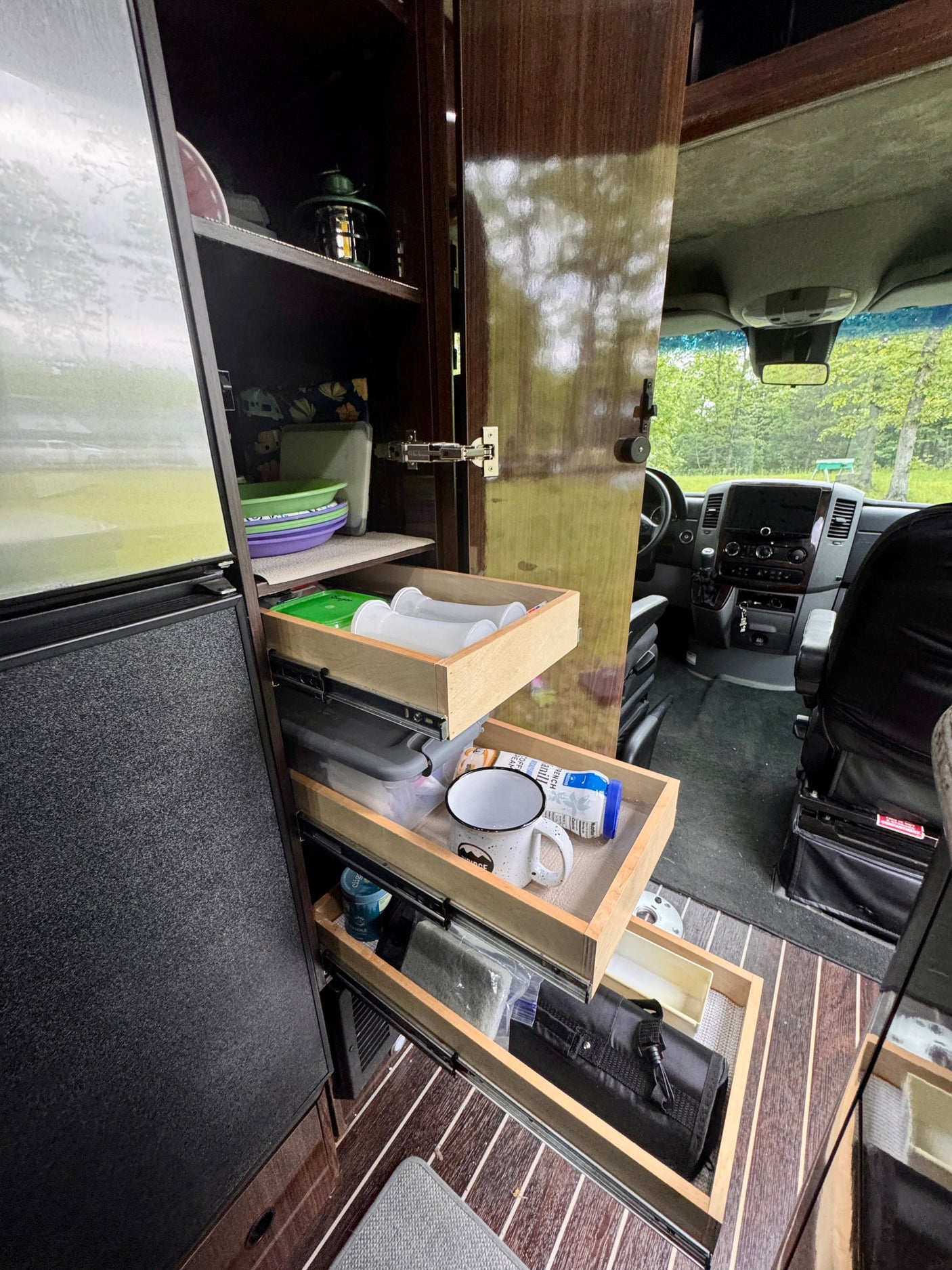 RV rental kitchen with pull-out drawers for organized plates, mugs, and supplies, plus a driver's cockpit view.