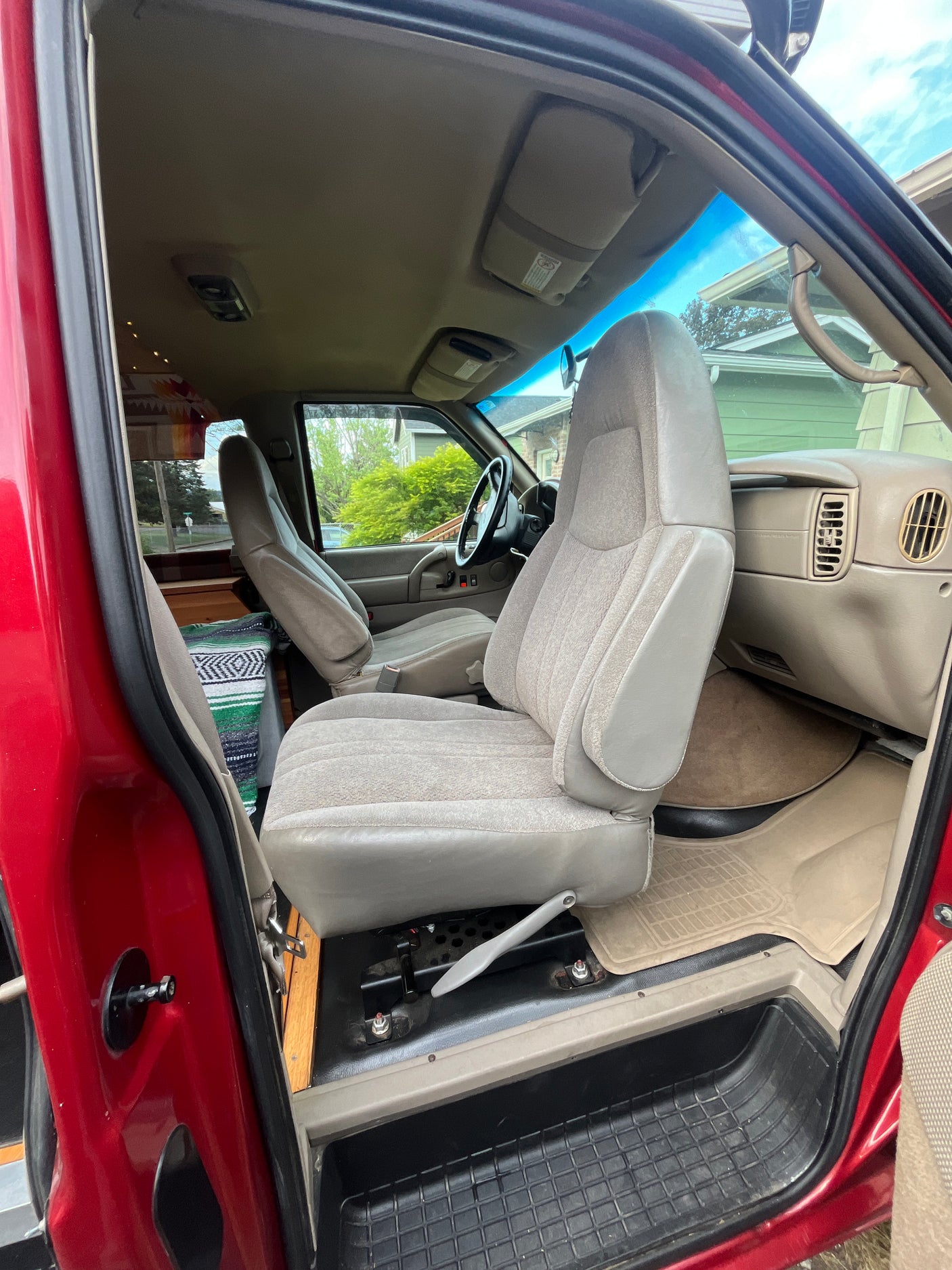 Red van interior for RV rental: front seats, dash, & converted living space visible. Explore in comfort.