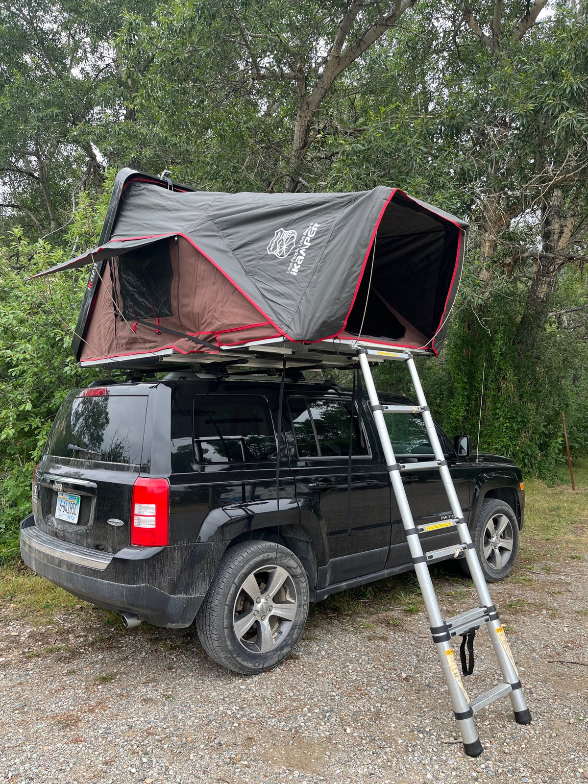 parked on grass. Perfect for an RV rental camping adventure!|A black Jeep Patriot with an iKamper rooftop tent set up for camping — photo 2