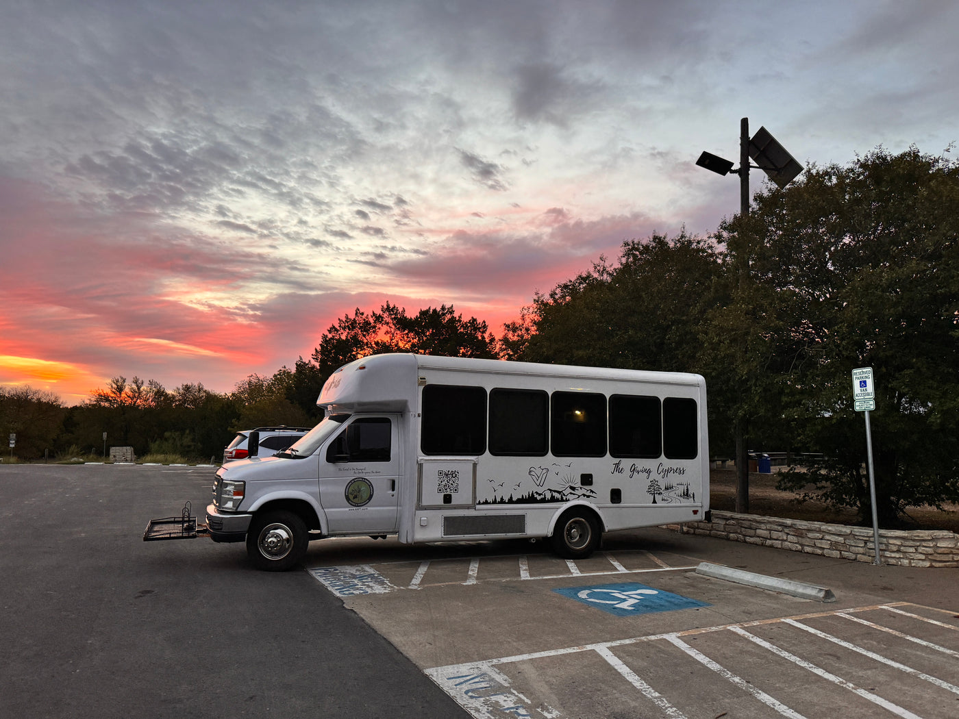 White, accessible RV rental bus parked at sunset, transporting guests for a forest therapy program. — photo 19