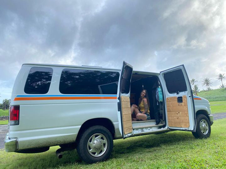 This RV rental campervan, with a smiling woman inside, offers adventure and van life travel.
