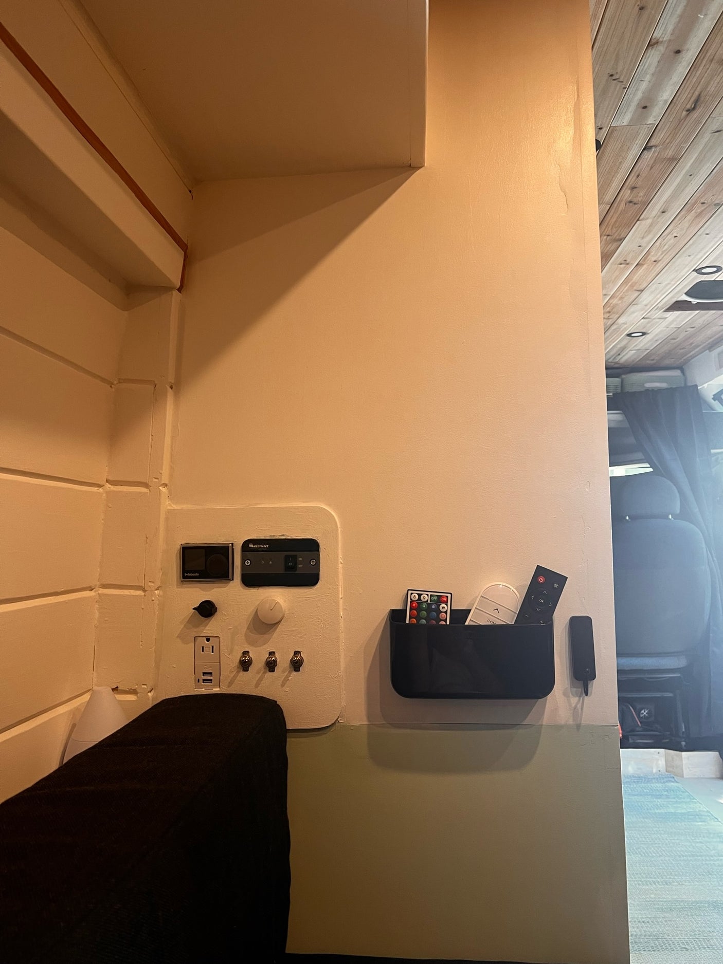 RV rental interior: Renogy & Webasto controls, AC/USB outlets, and remotes organized in a practical camper van living space.
