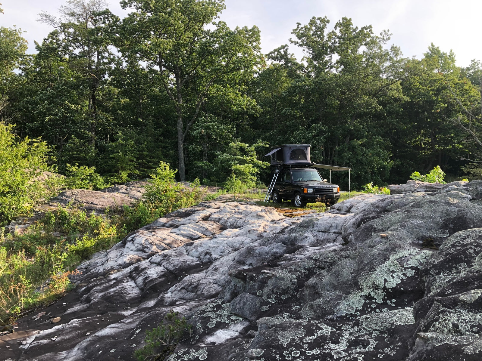 ready for an overlanding adventure. A unique RV rental experience in nature.|Land Rover with rooftop tent and awning on rocky terrain