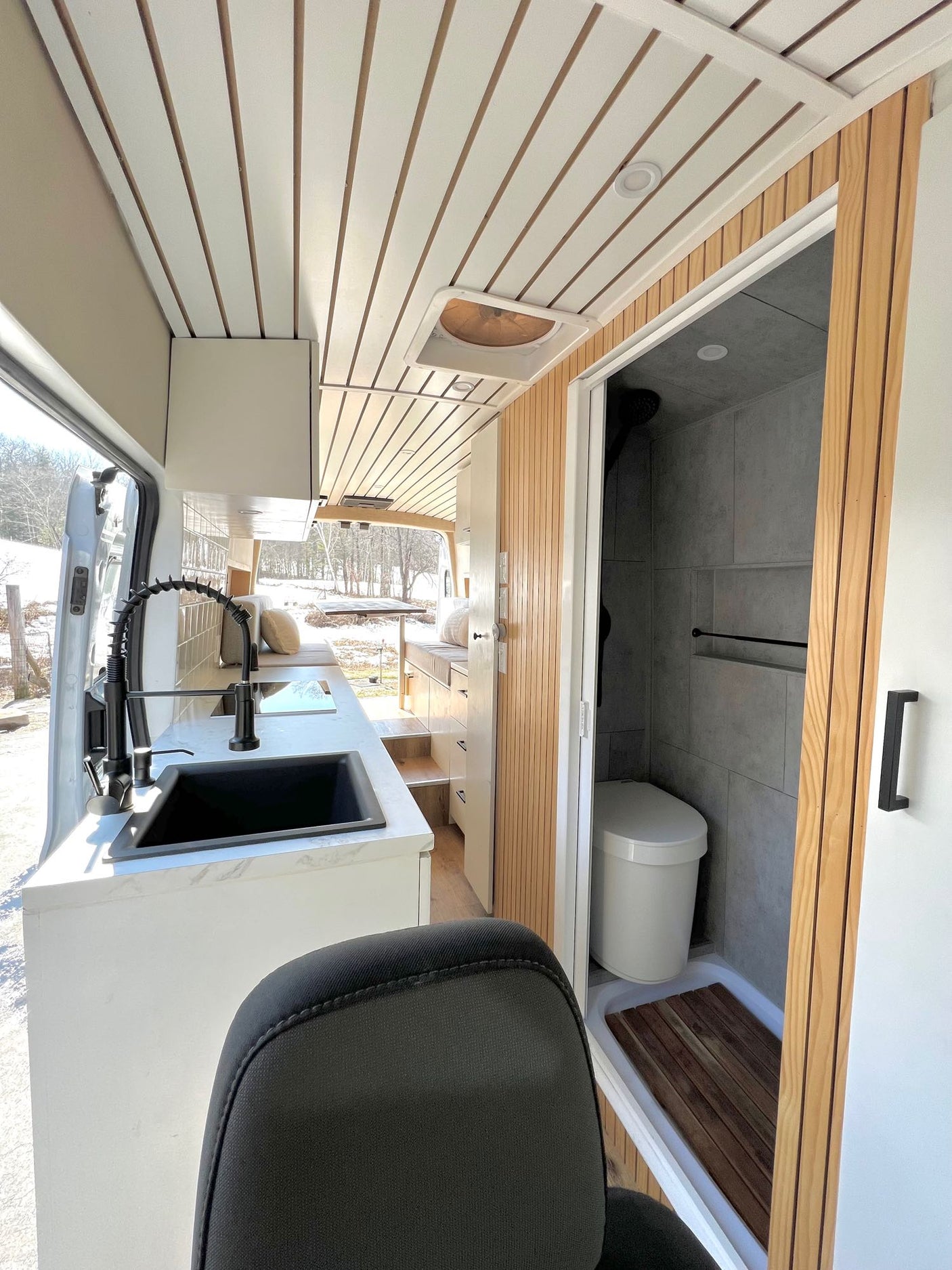 Explore this RV rental's modern camper van interior: stylish kitchen with black sink, and compact tiled bathroom.
