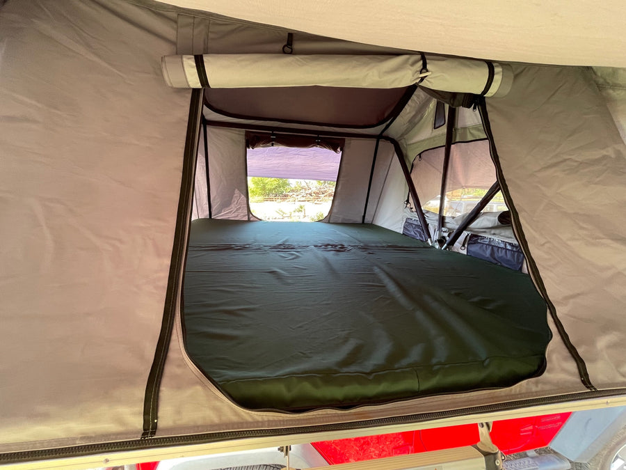 Comfortable interior of a rooftop tent with a mattress and open windows, ideal for an RV rental camping adventure.