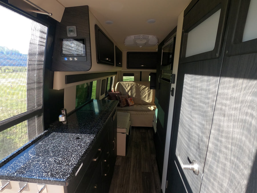 Spacious RV rental interior featuring a full kitchen, comfortable living area, and scenic window views.