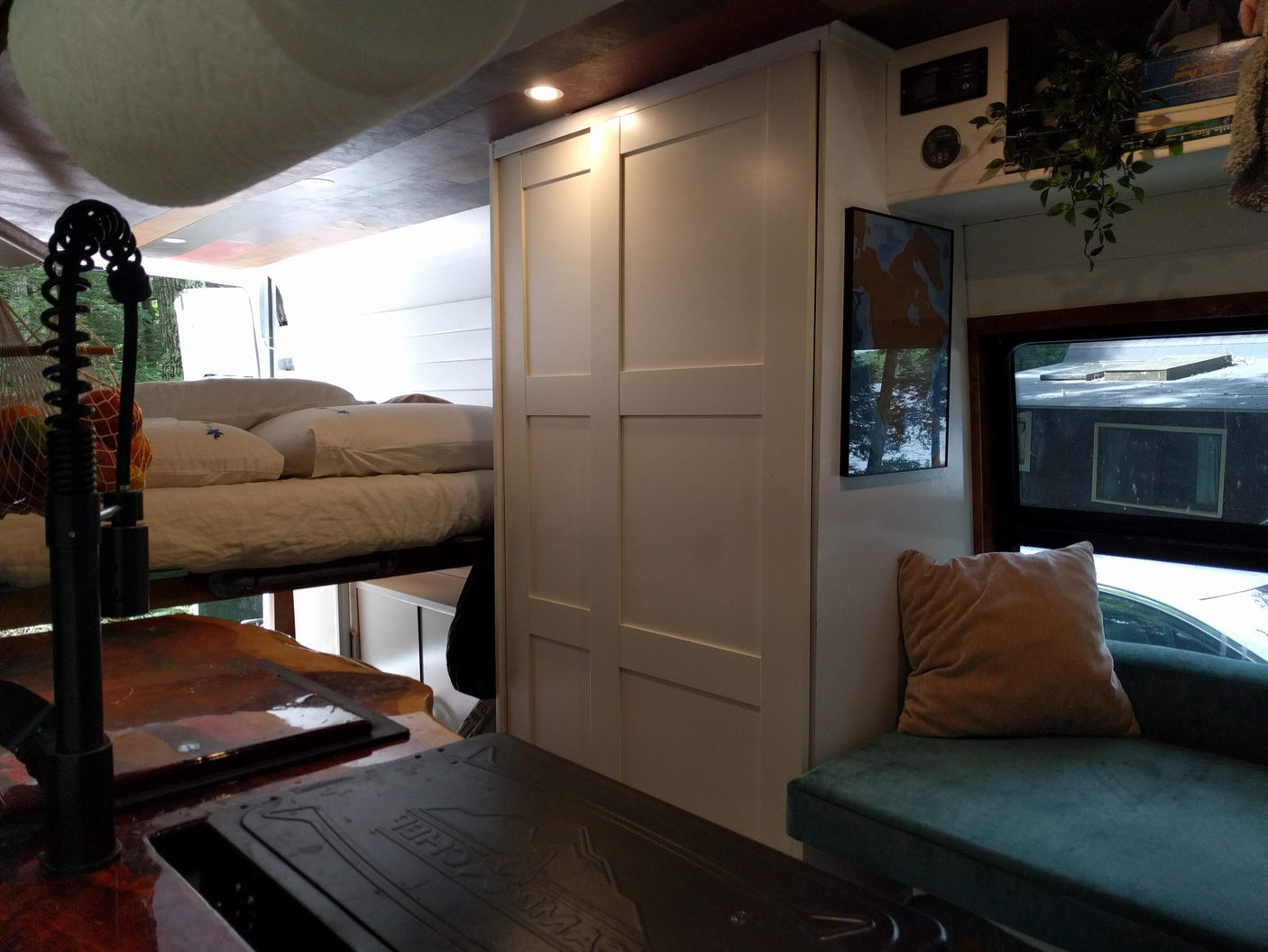 Step into this cozy rv rental, showcasing a built-in kitchen, elevated bed, and lounge area. White cabinets offer smart storage.