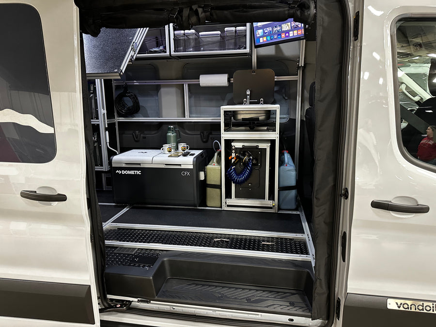 This RV rental shows a fully equipped camper van interior with a Dometic fridge, sink, and TV for mobile living.