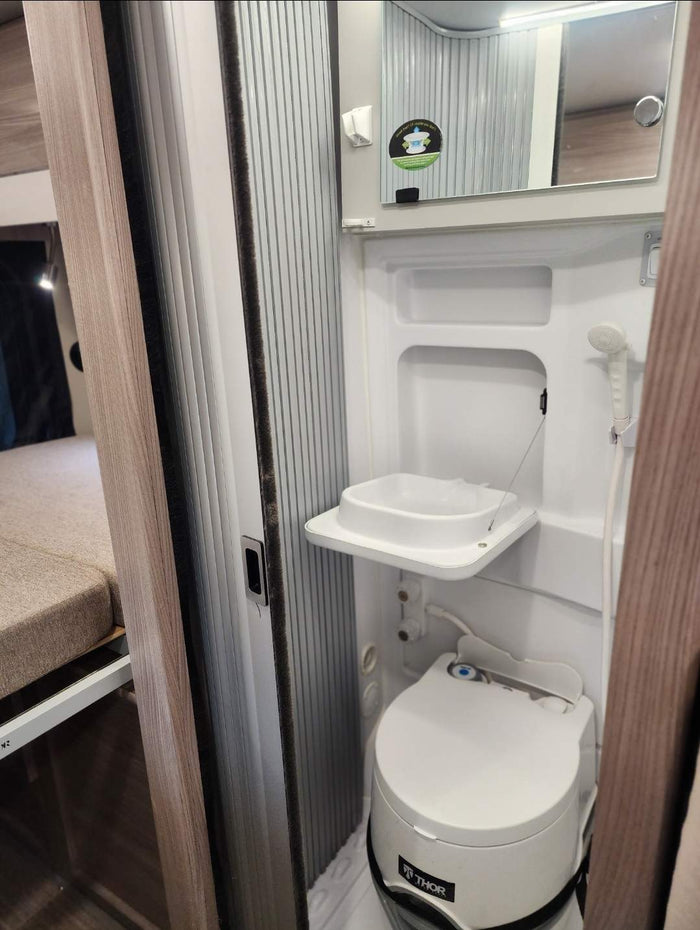 parked on a snowy road amidst trees. Ideal for an rv rental trip.|Dark gray Ram ProMaster camper van with pop-top (1 skylight