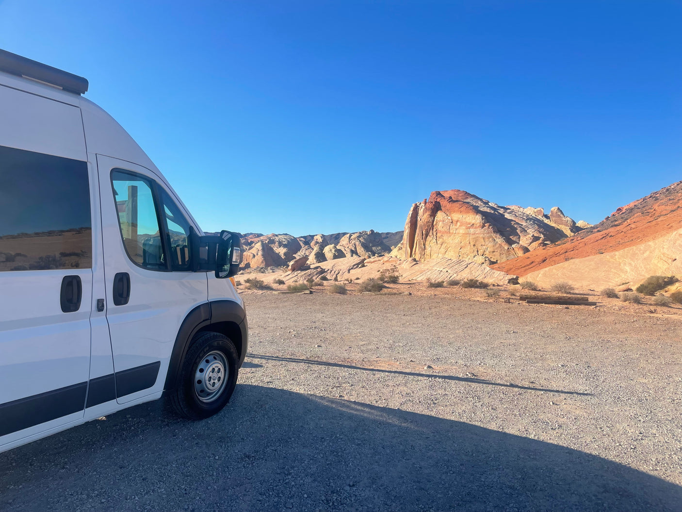 RV rental parked in a stunning desert landscape with vibrant, layered rock formations under a clear sky. Perfect for a road trip!