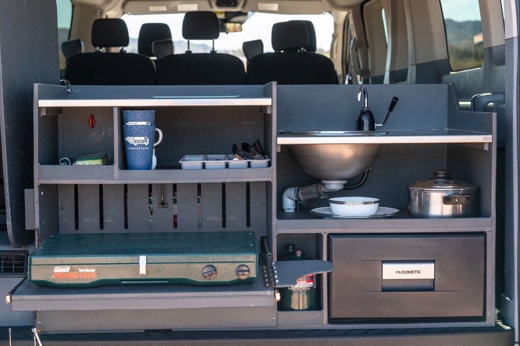 and ample storage for travel.|RV rental: Interior of a camper van with a neatly made bed and pillows — photo 3