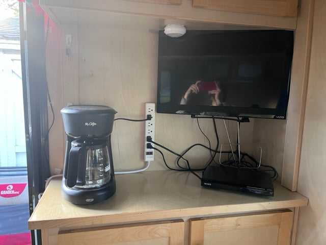 Cozy RV rental setup: Mr. Coffee, Vizio TV, Sony DVD player, and power strip on a wooden counter.