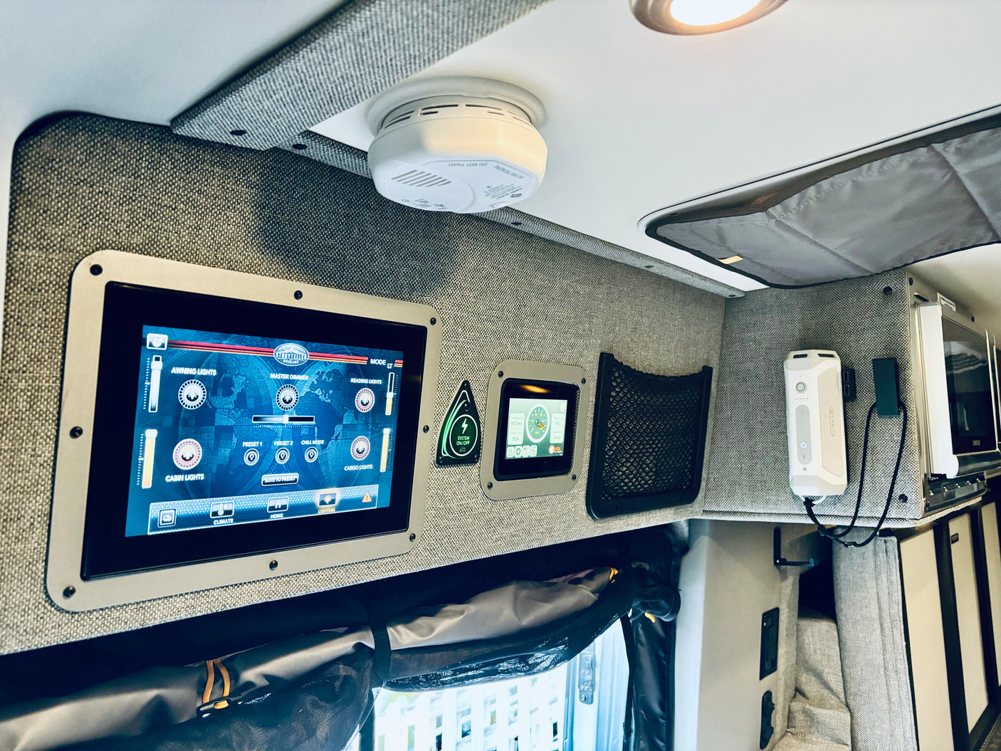 Explore smart tech in an RV rental: a Storyteller Overland control panel for lights & climate, microwave, and system displays.