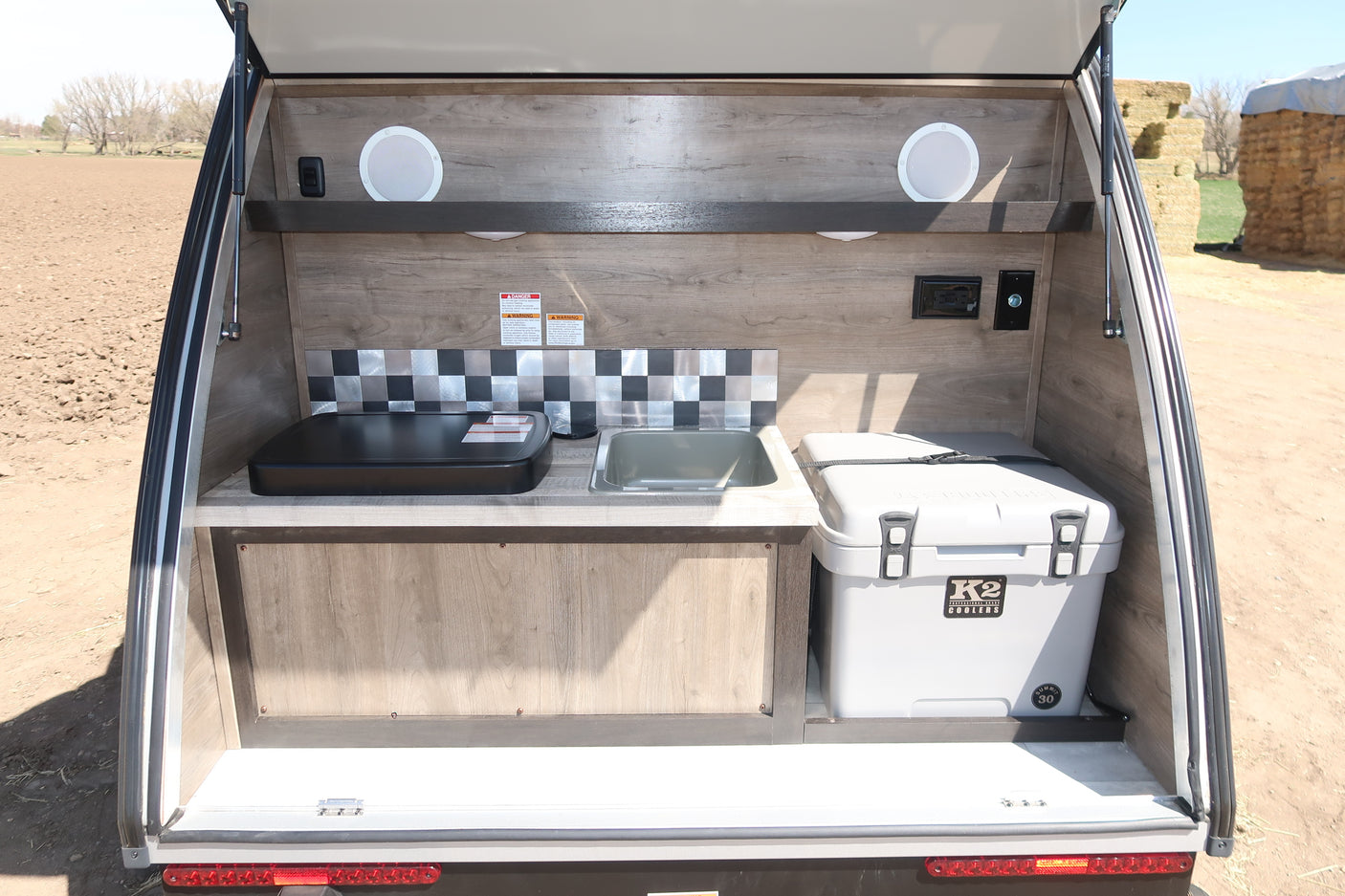 This RV rental's outdoor kitchen features a griddle, sink, and K2 cooler, perfect for camping and outdoor adventures.