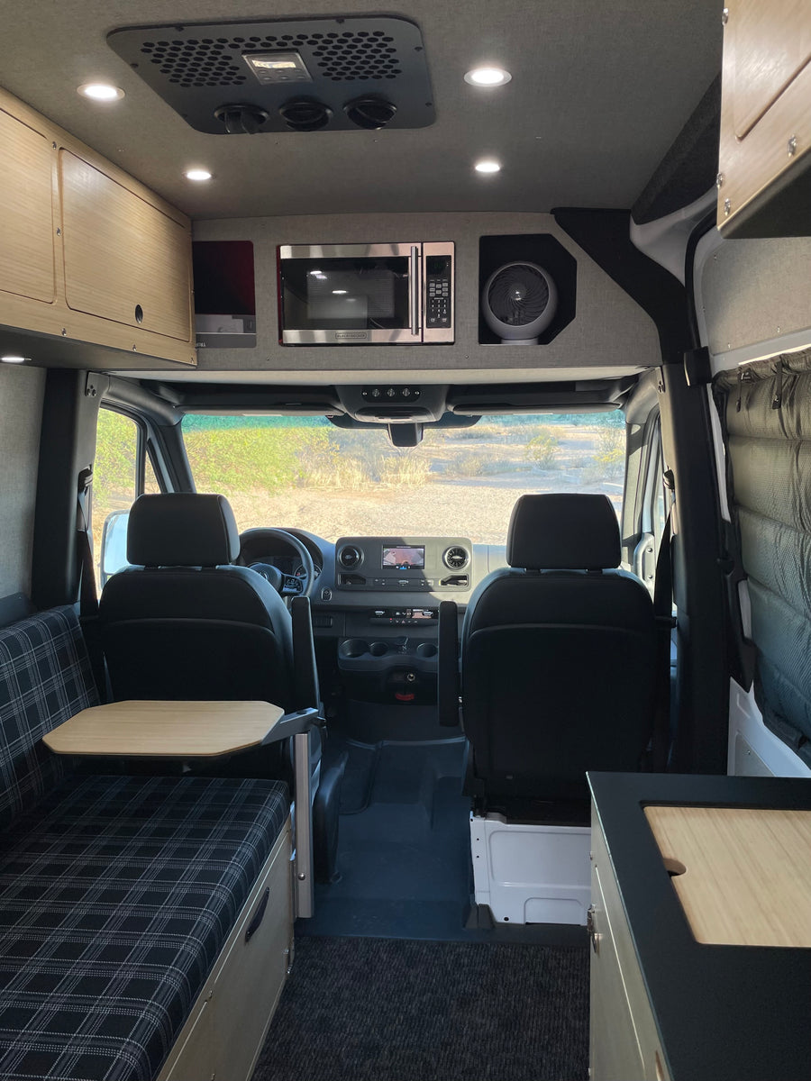 Modern RV rental interior: kitchen, dining, seating & front cabin for travelers.