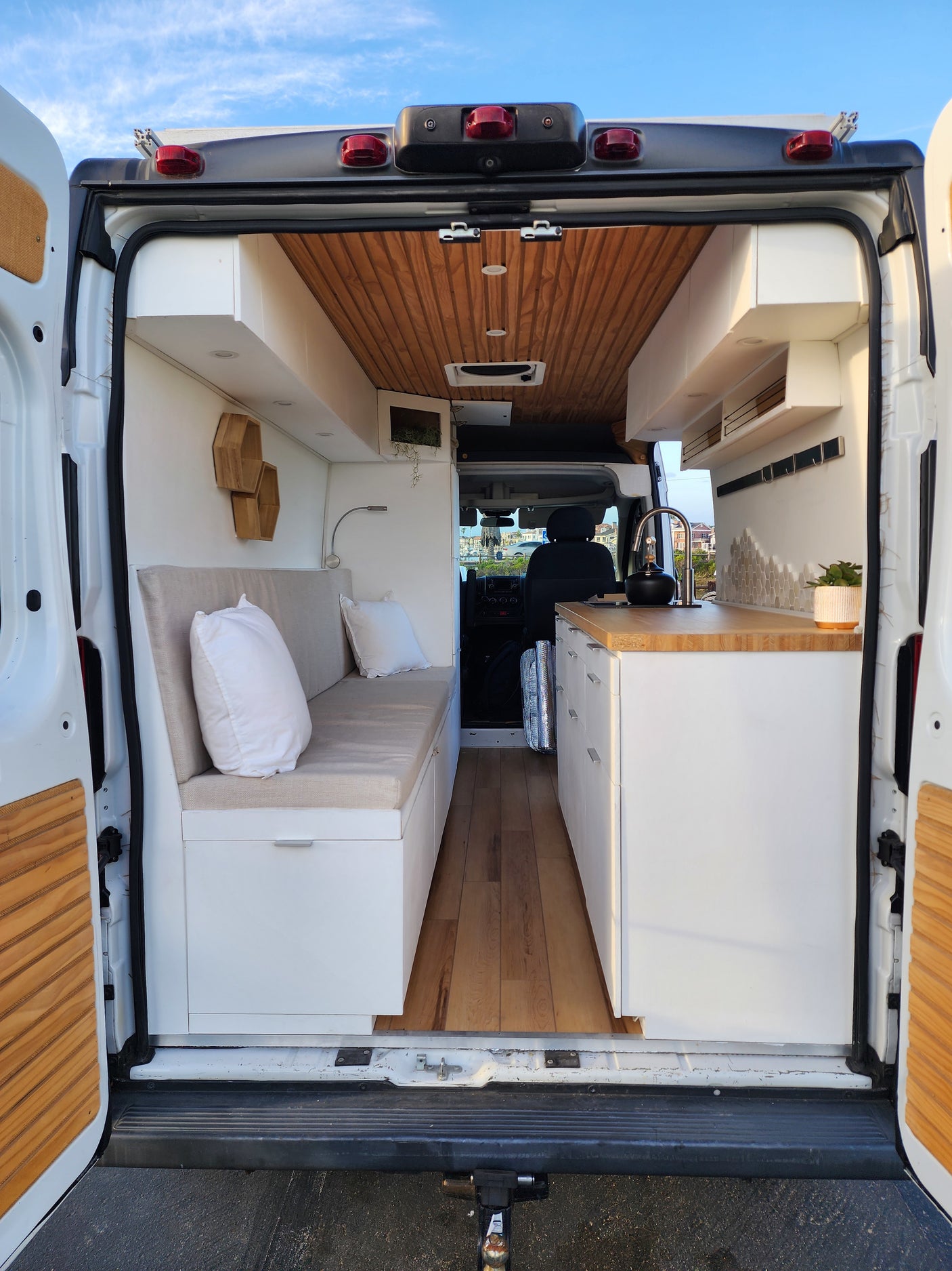 Inside an rv rental: a modern camper van with wood accents, featuring a bed, kitchen, and smart storage solutions.