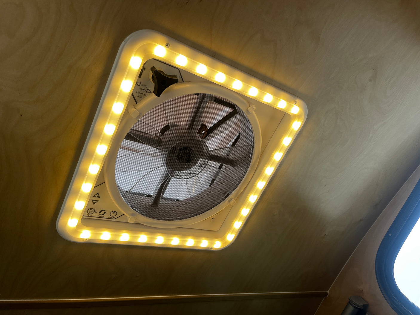 Bright LED lights illuminate a powered ceiling vent fan in an RV rental, providing light and air circulation for travelers.