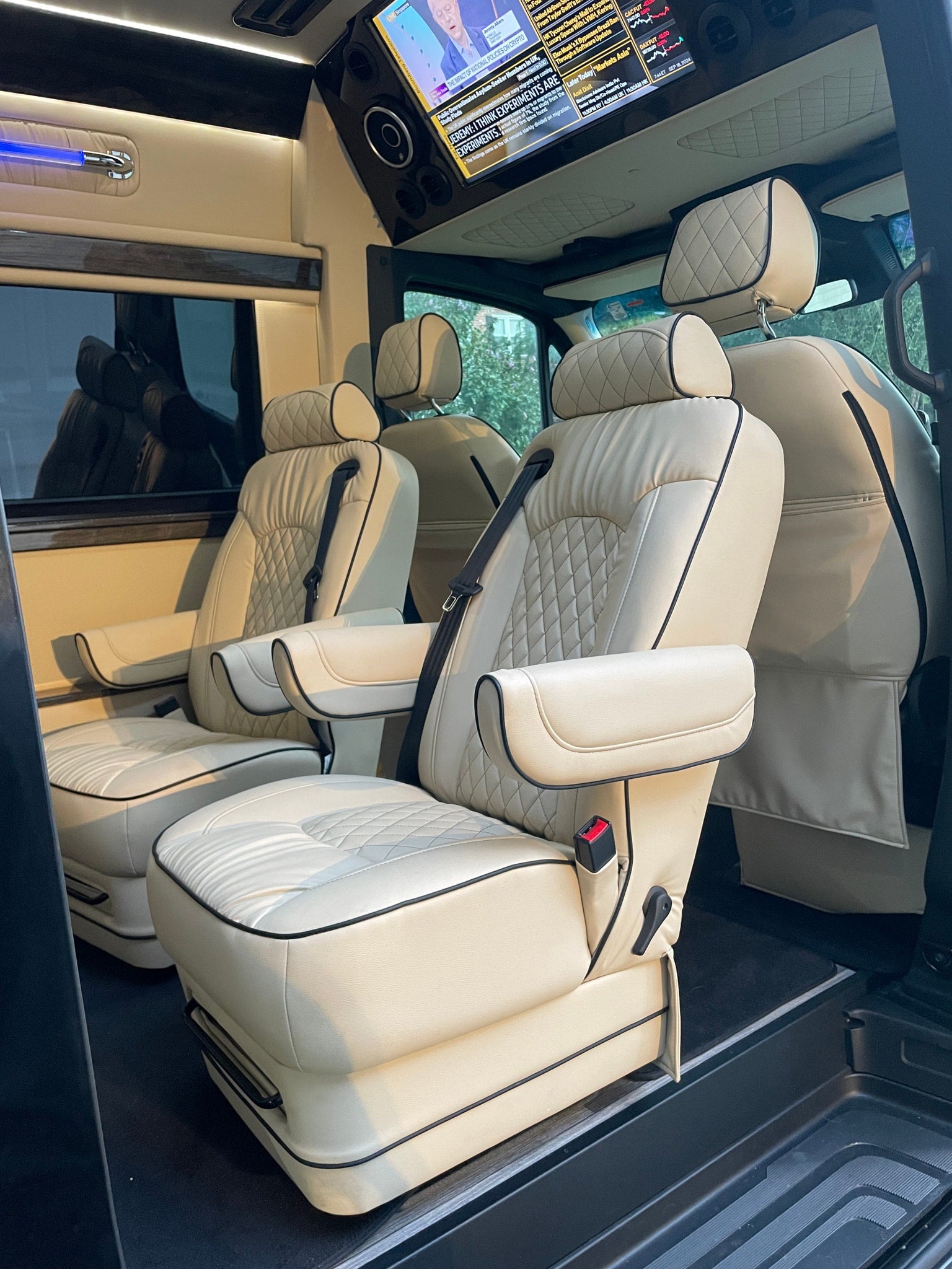 surrounded by tall pine trees.|Black Mercedes-Benz Sprinter van