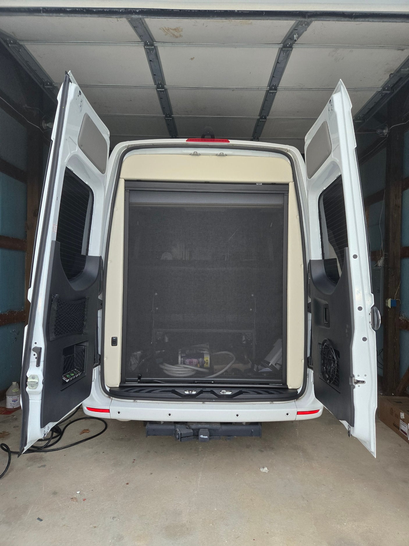 part of a modern kitchen in this comfortable RV rental.|RV rental kitchen featuring a stainless steel microwave oven above an open wooden cabinet
