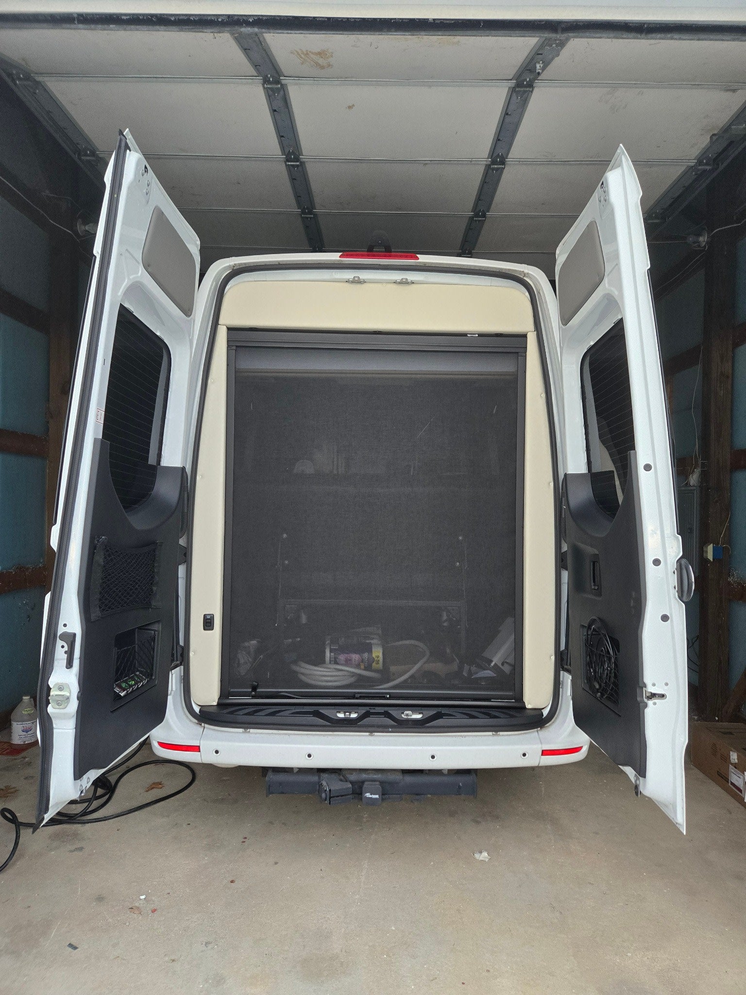 part of a modern kitchen in this comfortable RV rental.|RV rental kitchen featuring a stainless steel microwave oven above an open wooden cabinet