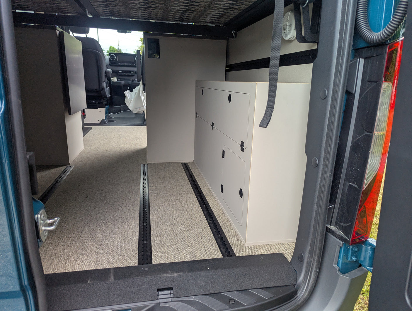 RV rental: Spacious camper van interior with modular cabinets, comfy carpet, and track flooring system.