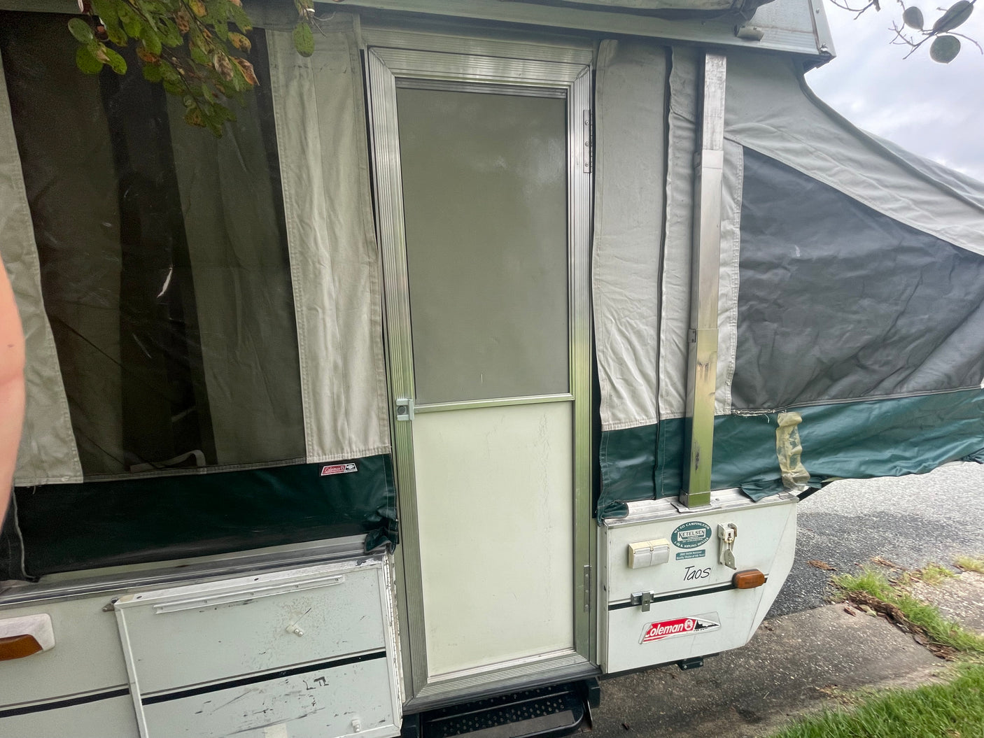 A Coleman pop-up camper RV rental, with canvas walls and entrance door, stands ready for a memorable camping trip.