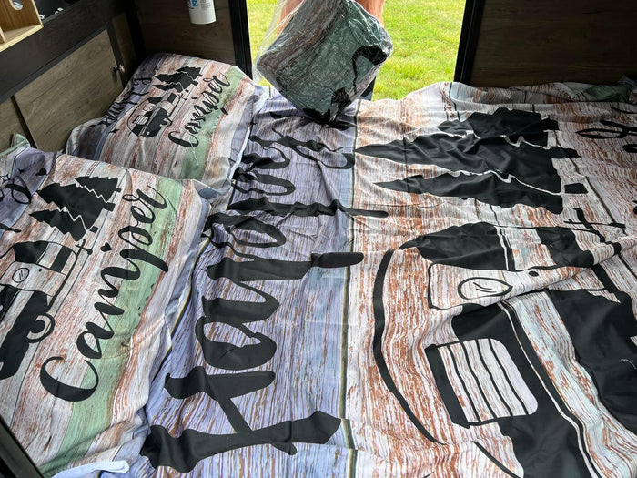 Rustic wood grain & camper-themed bedding in an RV rental. Perfect for your next camping adventure!