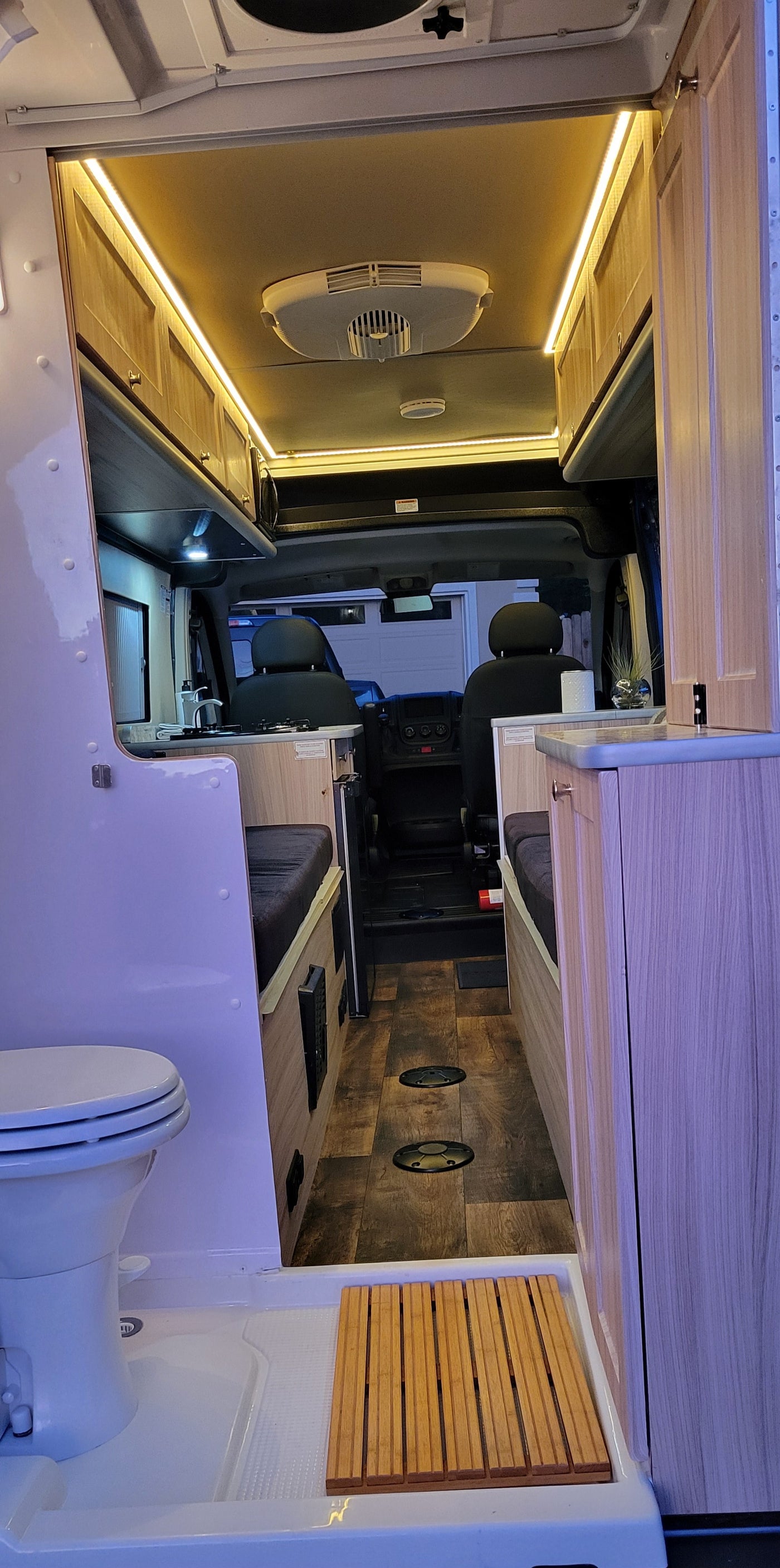 Inside a modern **rv rental**, featuring a compact kitchen, toilet, shower, and cozy sleeping/seating areas. — photo 11