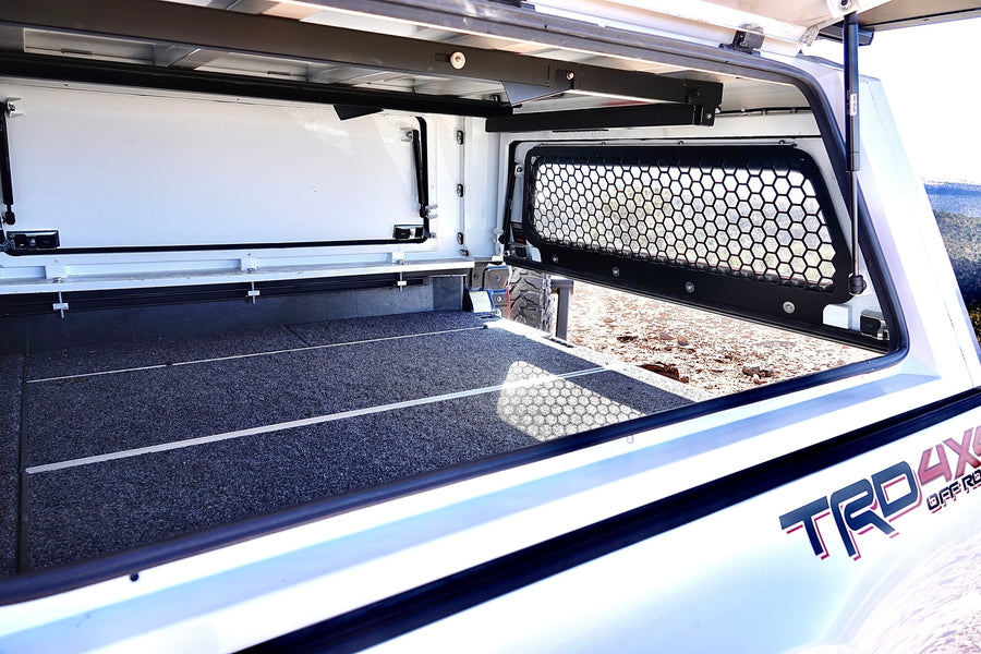 View inside an off-road truck camper, featuring a carpeted floor and a mesh window. Great for rv rental.